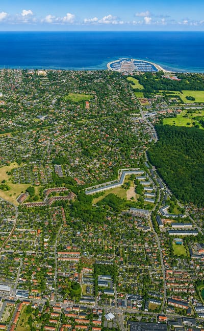 High aerial of Hørsholm's green suburban streets reaching a marina on the Øresund coast