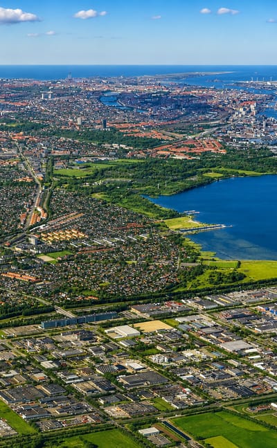 High aerial over Hvidovre, Denmark, with suburban sprawl, a lake and a power plant near Copenhagen