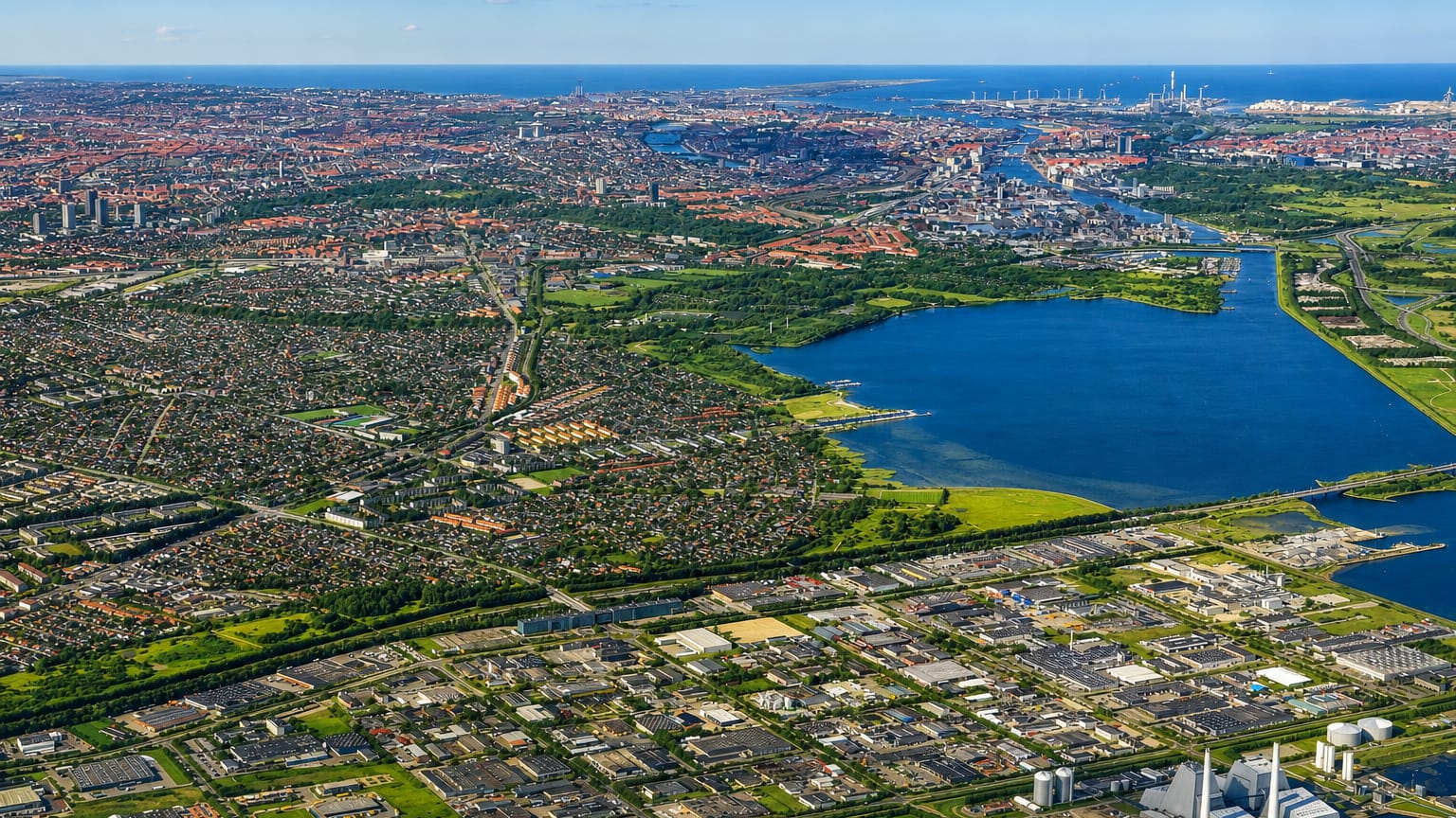 High aerial over Hvidovre, Denmark, with suburban sprawl, a lake and a power plant near Copenhagen