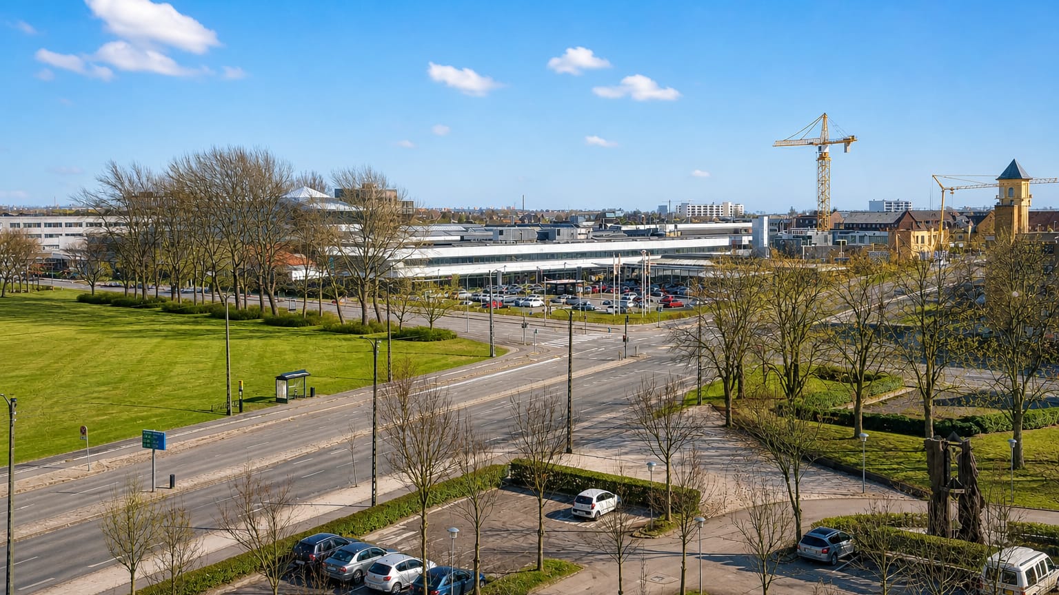Daytime view over Rødovre, Denmark: low-rise commercial buildings, tree-lined roads and green parkland under a blue sky.