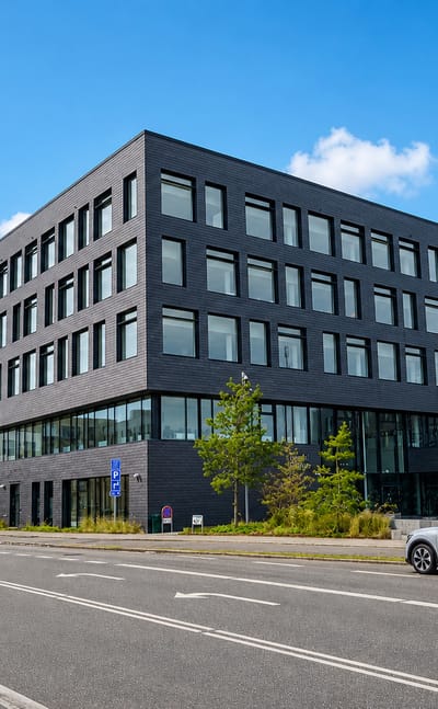 Modern dark-brick office building beside an empty street under a bright blue sky in Stenløse, Denmark