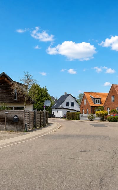 Sunlit residential street of brick and timber houses in suburban Taastrup, Denmark.
