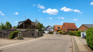 Sunlit residential street of brick and timber houses in suburban Taastrup, Denmark.