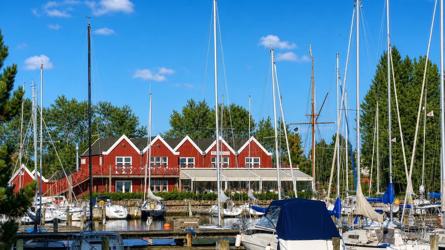 Sailboats moored in the marina in front of a red gabled clubhouse at Vallensbæk, Denmark