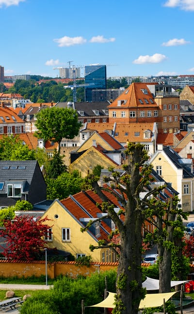 Rooftops of Frederiksbjerg in Aarhus, red-tiled houses and a residential tower under a blue summer sky