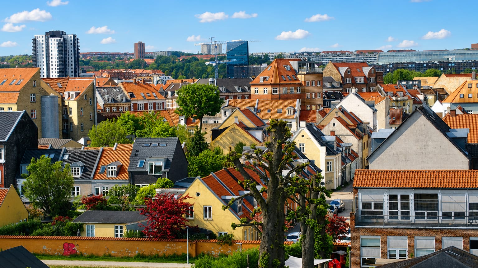 Rooftops of Frederiksbjerg in Aarhus, red-tiled houses and a residential tower under a blue summer sky