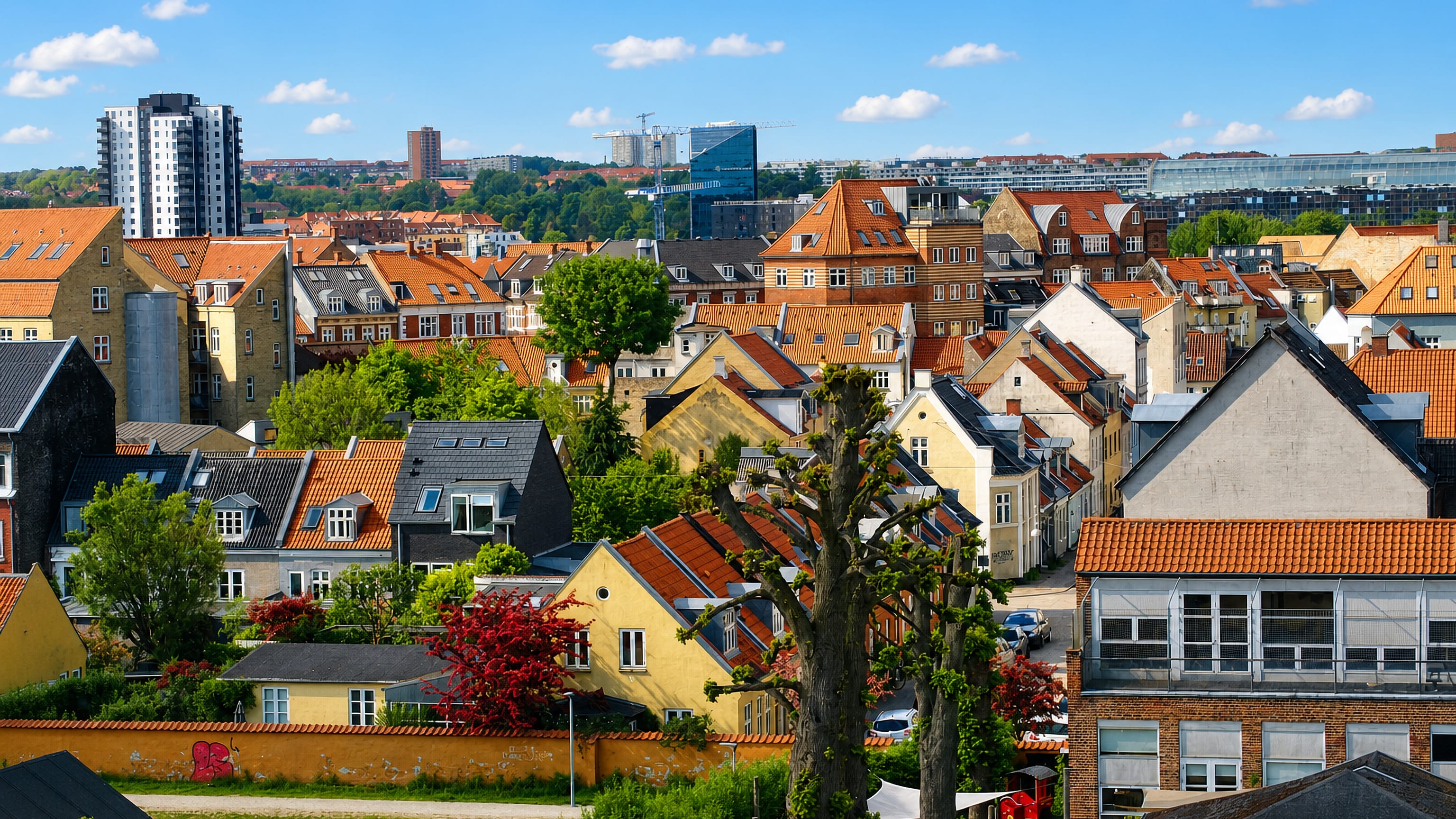 Rooftops of Frederiksbjerg in Aarhus, red-tiled houses and a residential tower under a blue summer sky