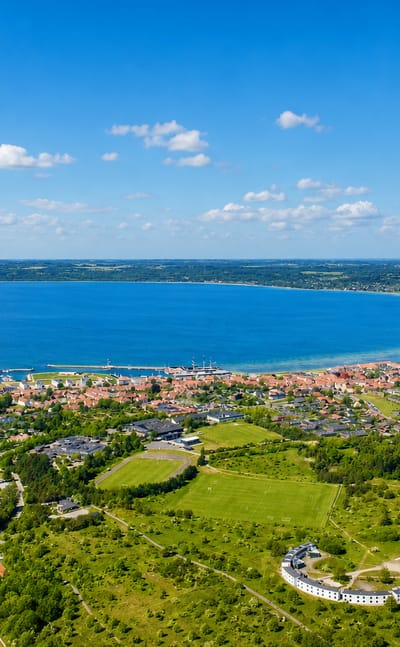 Aerial view of Ebeltoft on its curved Danish bay, with a harbour and town among green fields