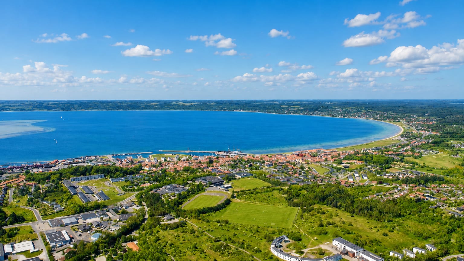 Aerial view of Ebeltoft on its curved Danish bay, with a harbour and town among green fields