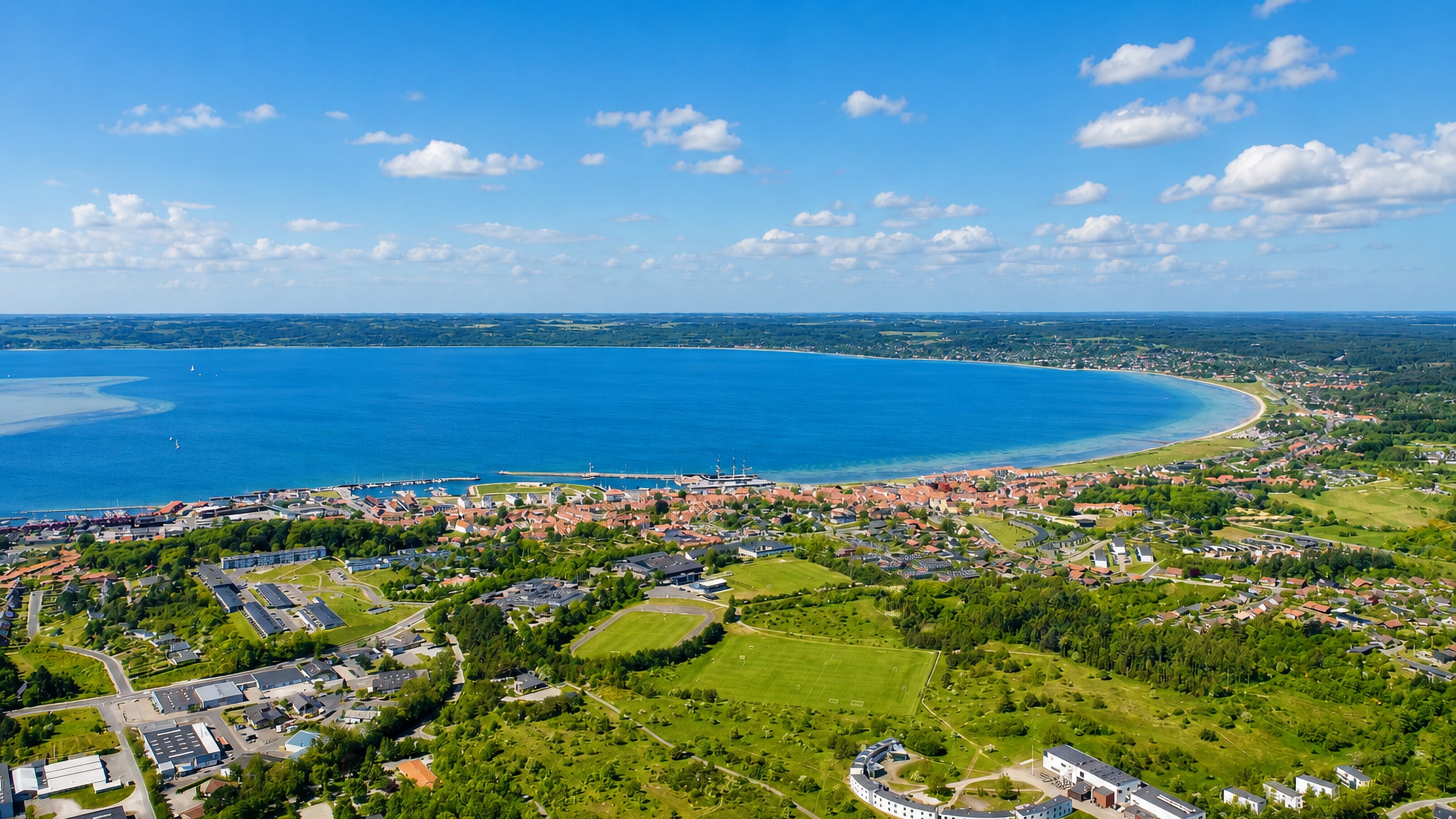 Aerial view of Ebeltoft on its curved Danish bay, with a harbour and town among green fields