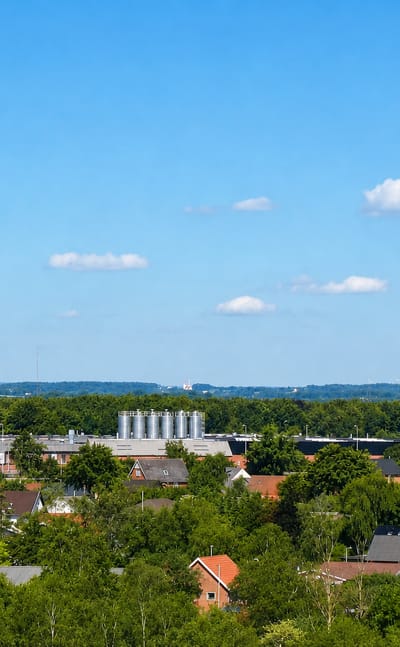 Herning townscape with the tall red-and-white lattice radio mast rising over houses and woodland in Denmark.