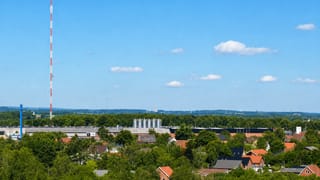 Herning townscape with the tall red-and-white lattice radio mast rising over houses and woodland in Denmark.
