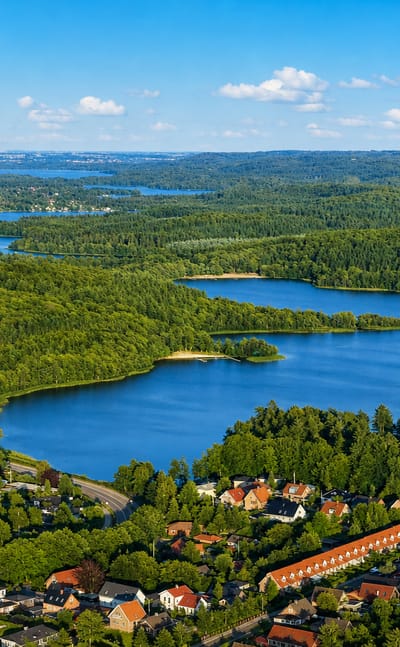 Aerial of Silkeborg town beside its forested lakes stretching into the Danish lake district