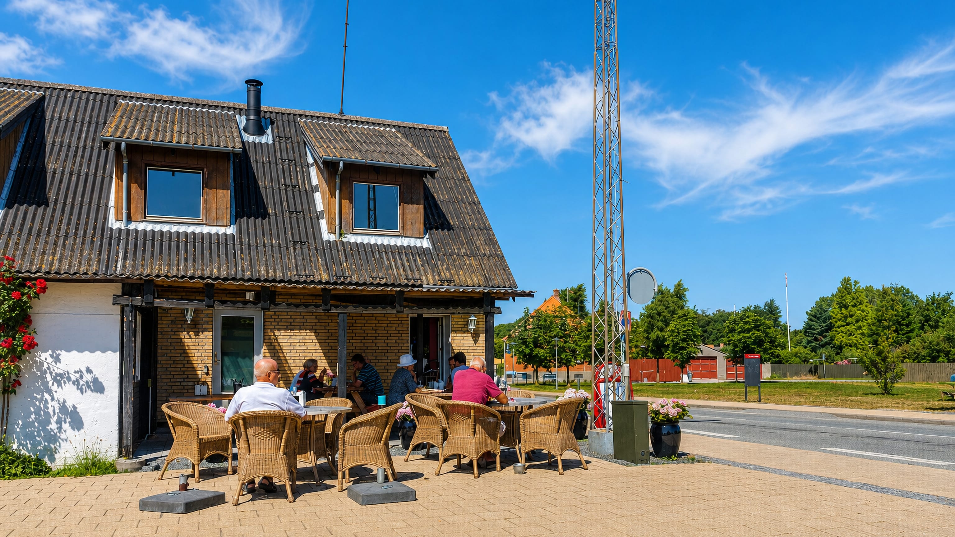 Guests at outdoor tables beside a yellow-brick house on the main road through Byrum on Læsø, Denmark.