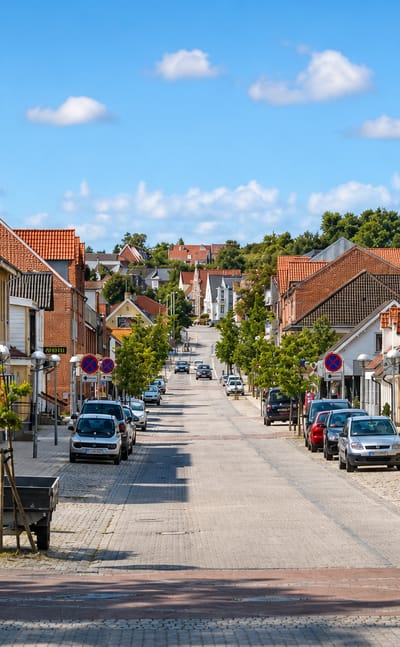 View down the sloping cobbled main street of Stovring, Denmark, lined with brick houses and shops