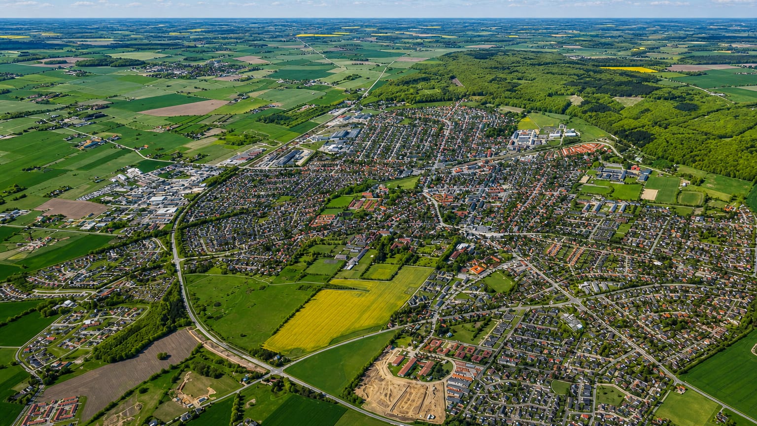 Aerial view of Haslev surrounded by green fields, yellow rapeseed and woodland on the Danish island of Zealand.
