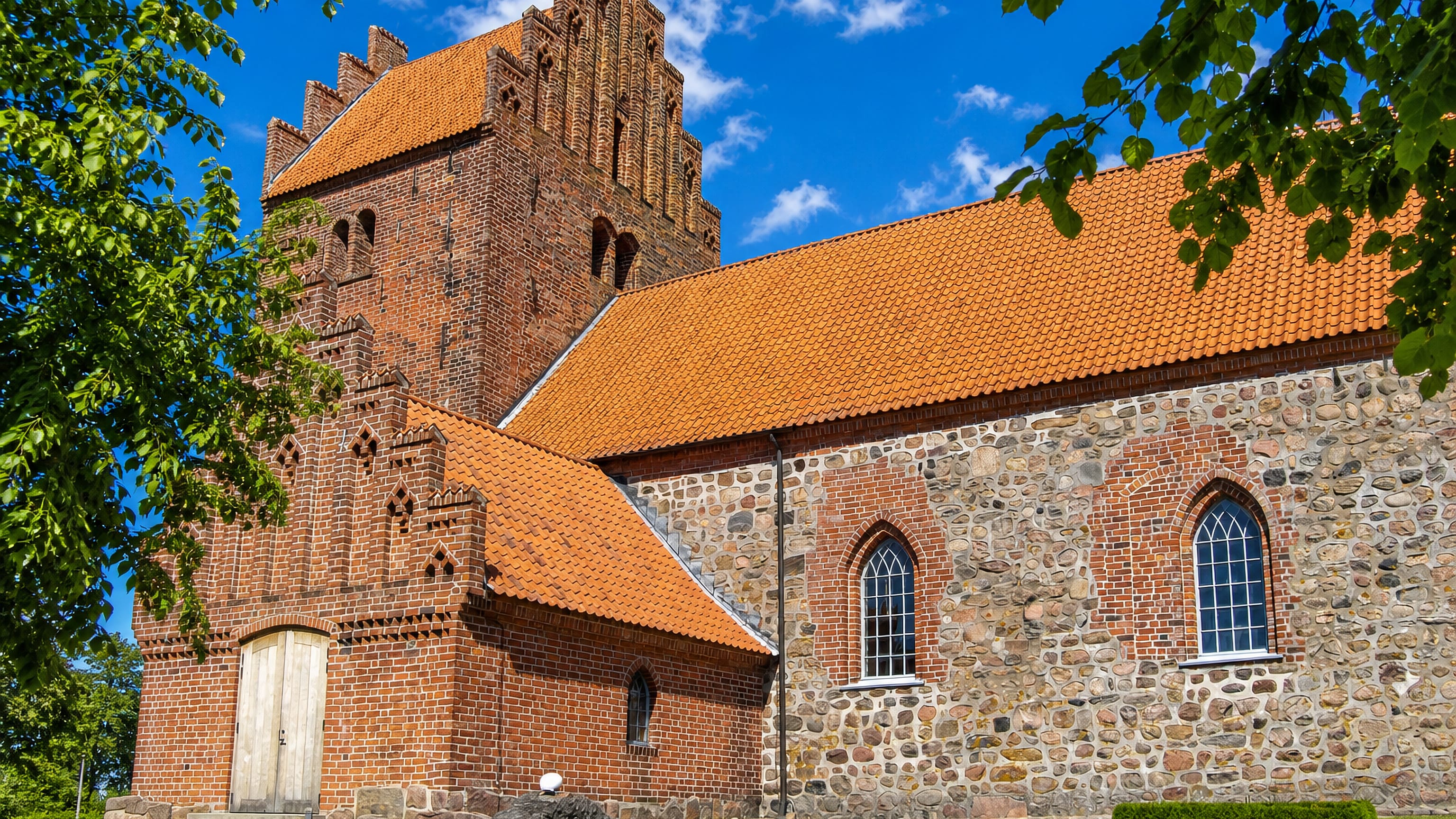 Medieval red-brick and fieldstone parish church with a stepped-gable tower at Højby on Zealand, Denmark.