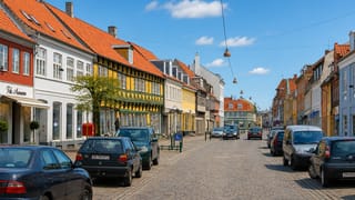 Cobbled old-town street in Koge lined with colorful half-timbered houses under a blue sky