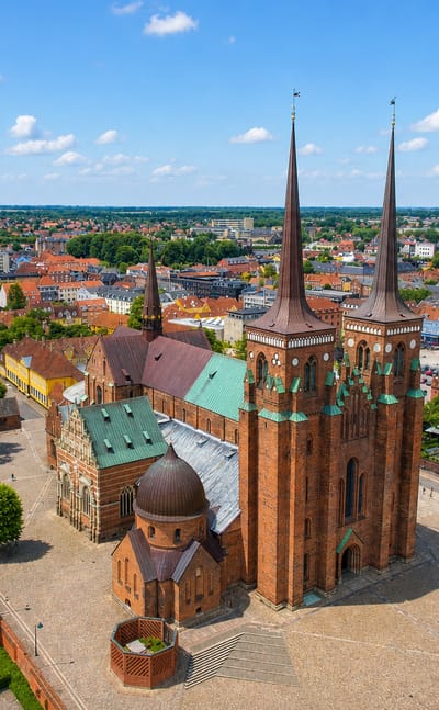 Roskilde's twin-spired red-brick Roskilde Cathedral rising over the surrounding old town under blue sky