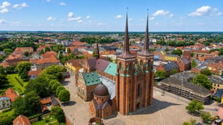 Roskilde's twin-spired red-brick Roskilde Cathedral rising over the surrounding old town under blue sky
