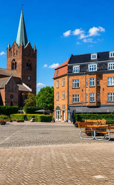 Sankt Mikkels Kirke and its tall spire rising over the red-brick town square in Slagelse, Denmark on a sunny day