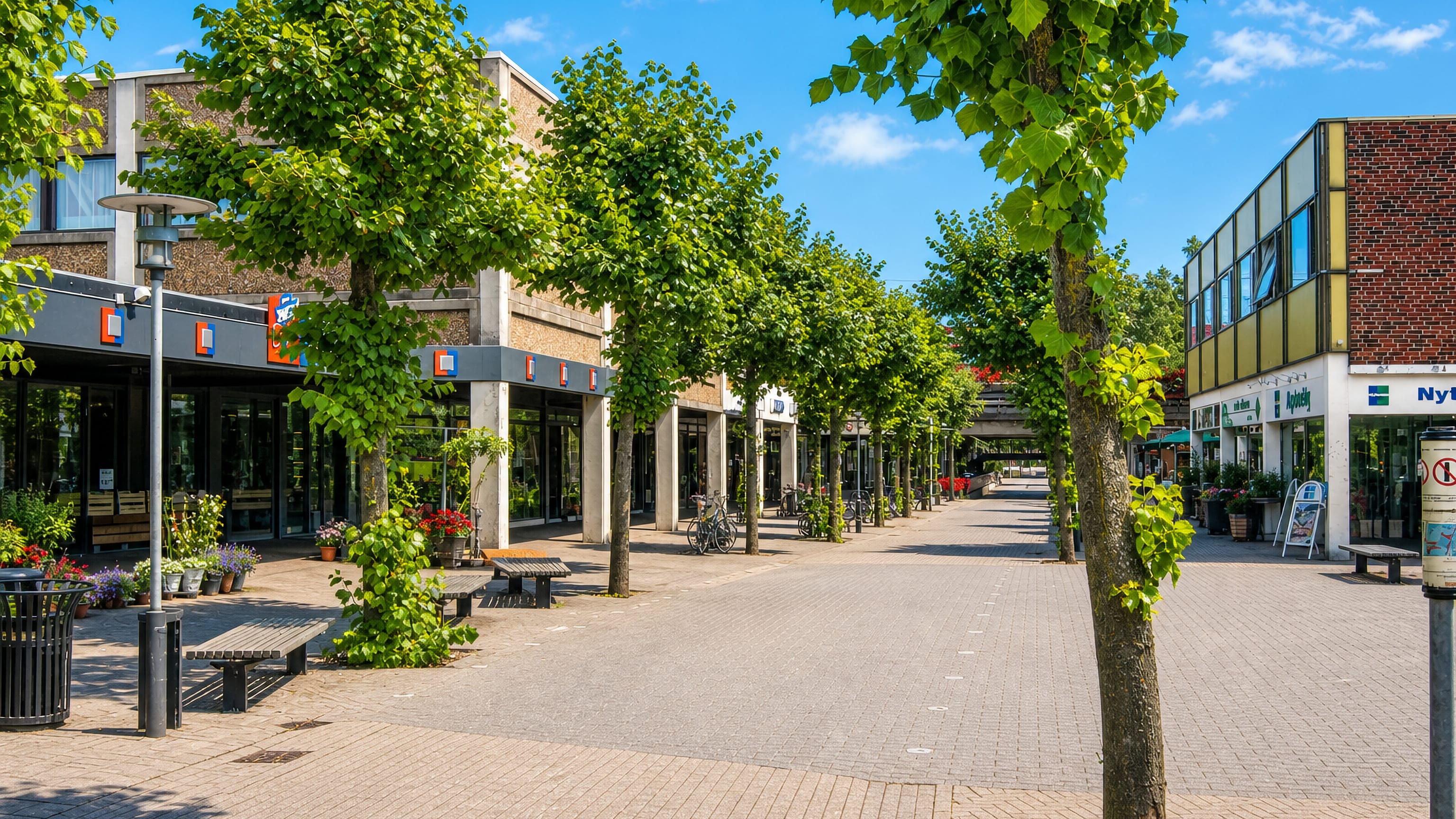 Tree-lined pedestrian shopping plaza with low modern buildings and benches in Solrød, Denmark