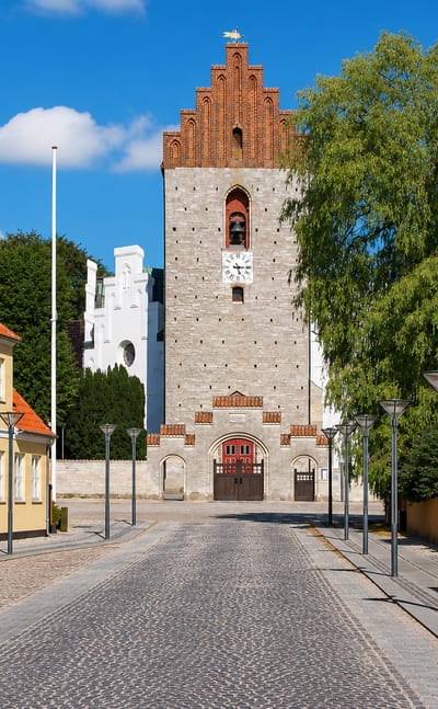 Cobbled street in Store Heddinge, Denmark, leading to the town's distinctive octagonal medieval church tower.