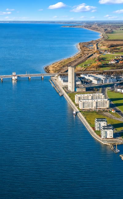 Aerial view of Vordingborg, Denmark, with a waterfront tower, marina and a bridge across the blue sound.