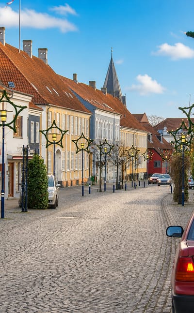 Cobbled historic street with pastel townhouses and star decorations in Assens, Denmark.