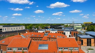 Aerial view over the red-tiled rooftops and modern buildings of Billund, Denmark, under a blue summer sky.
