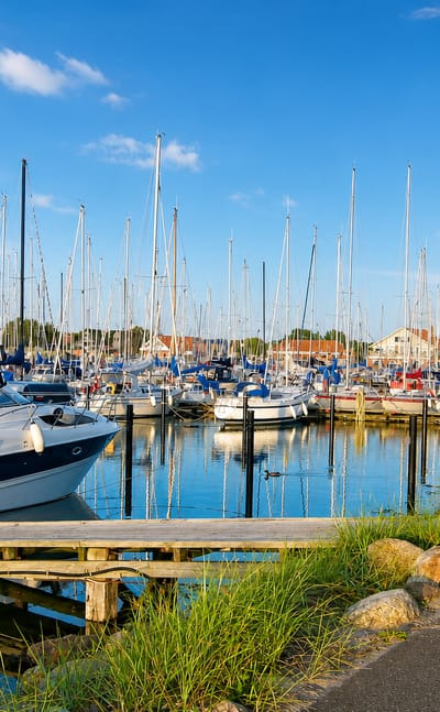 Marina full of moored sailboats with harbour buildings behind in Bogense, Denmark.