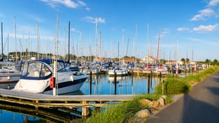Marina full of moored sailboats with harbour buildings behind in Bogense, Denmark.
