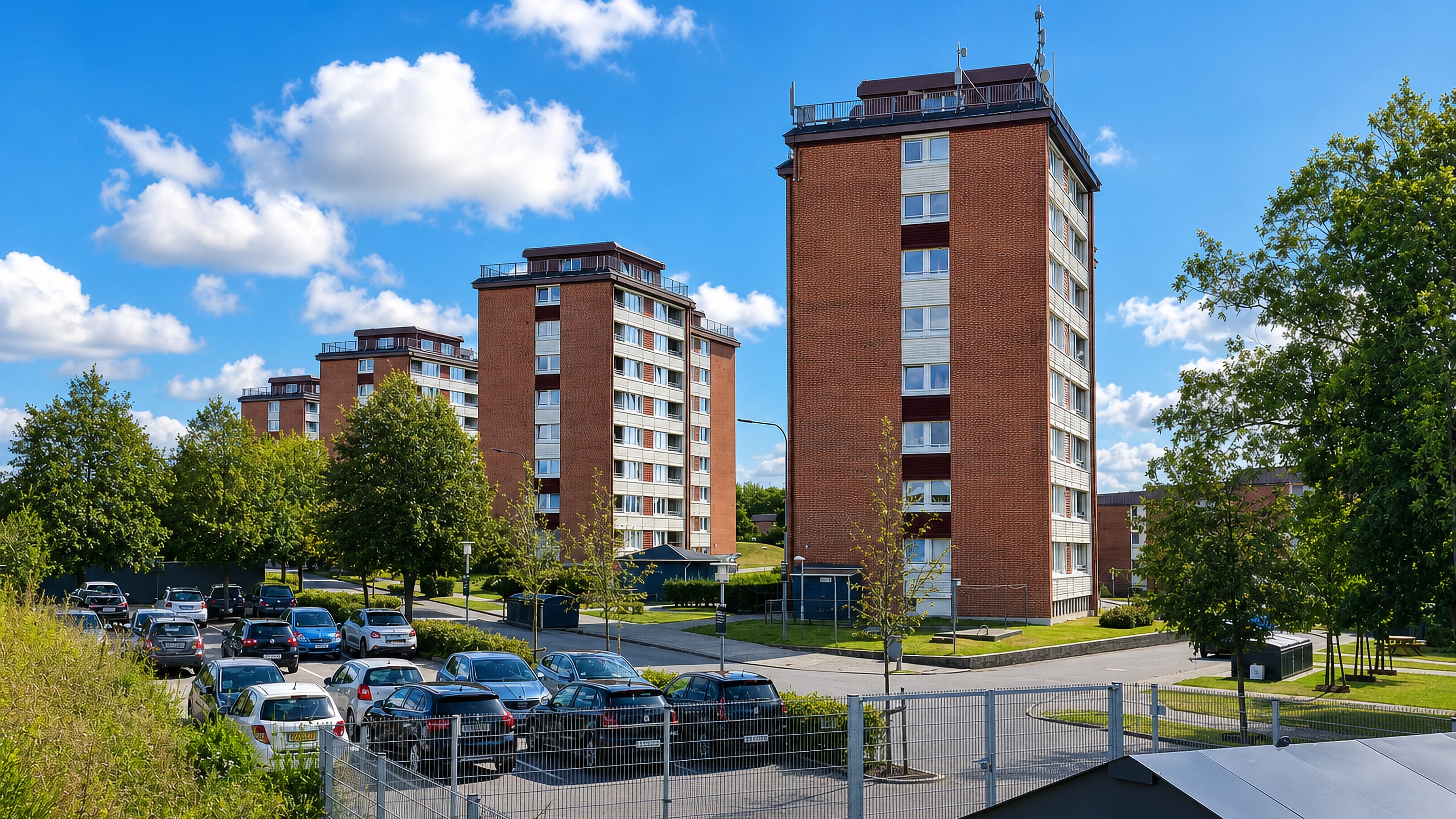 Red-brick apartment towers above a tree-lined car park in Jerne, a residential quarter of Esbjerg, Denmark.