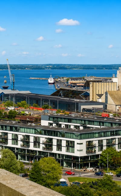 Kolding waterfront with harbour silos, marina and a modern apartment block beside the fjord in Denmark.