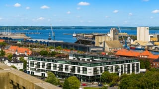 Kolding waterfront with harbour silos, marina and a modern apartment block beside the fjord in Denmark.