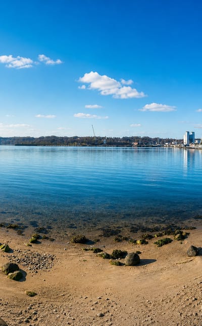 Beach on Vejle Fjord, Denmark, with the Wave waterfront apartments and fjord bridge across the water