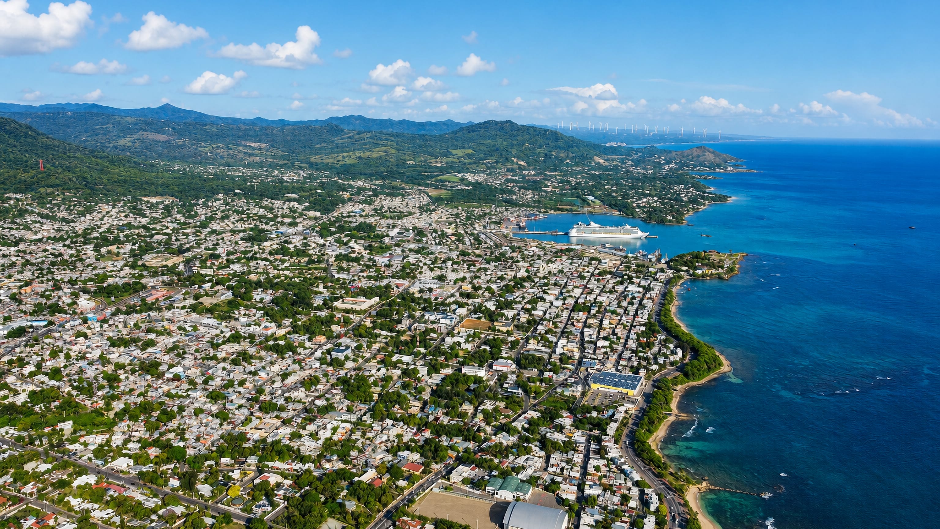 Aerial view of Puerto Plata, Dominican Republic, its grid of houses meeting turquoise water and a cruise port.