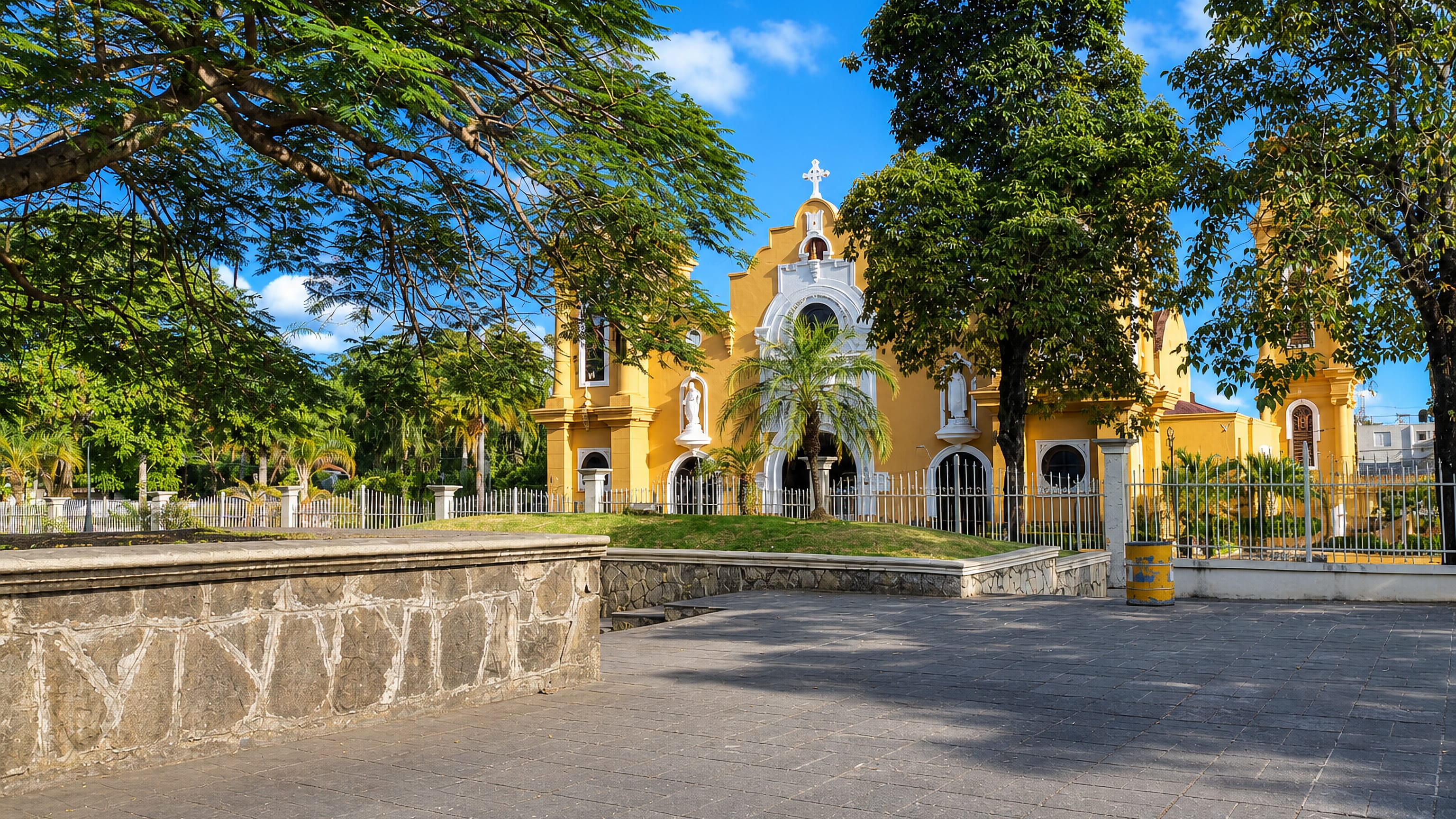 The yellow colonial-style parish church behind its garden fence in San Cristobal, Dominican Republic.