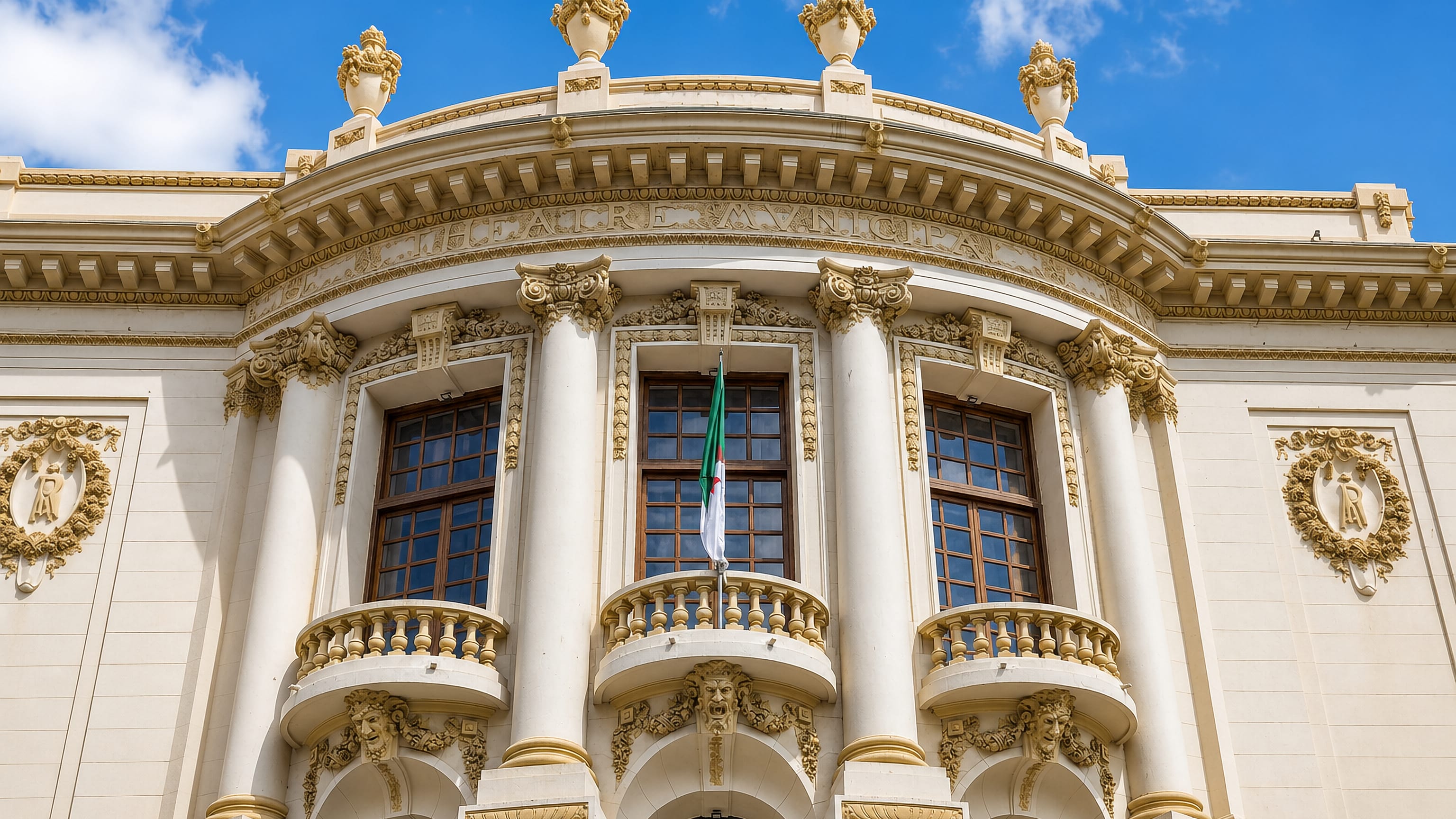 Ornate facade of the municipal theatre in Skikda, Algeria, with the Algerian flag on its balcony.