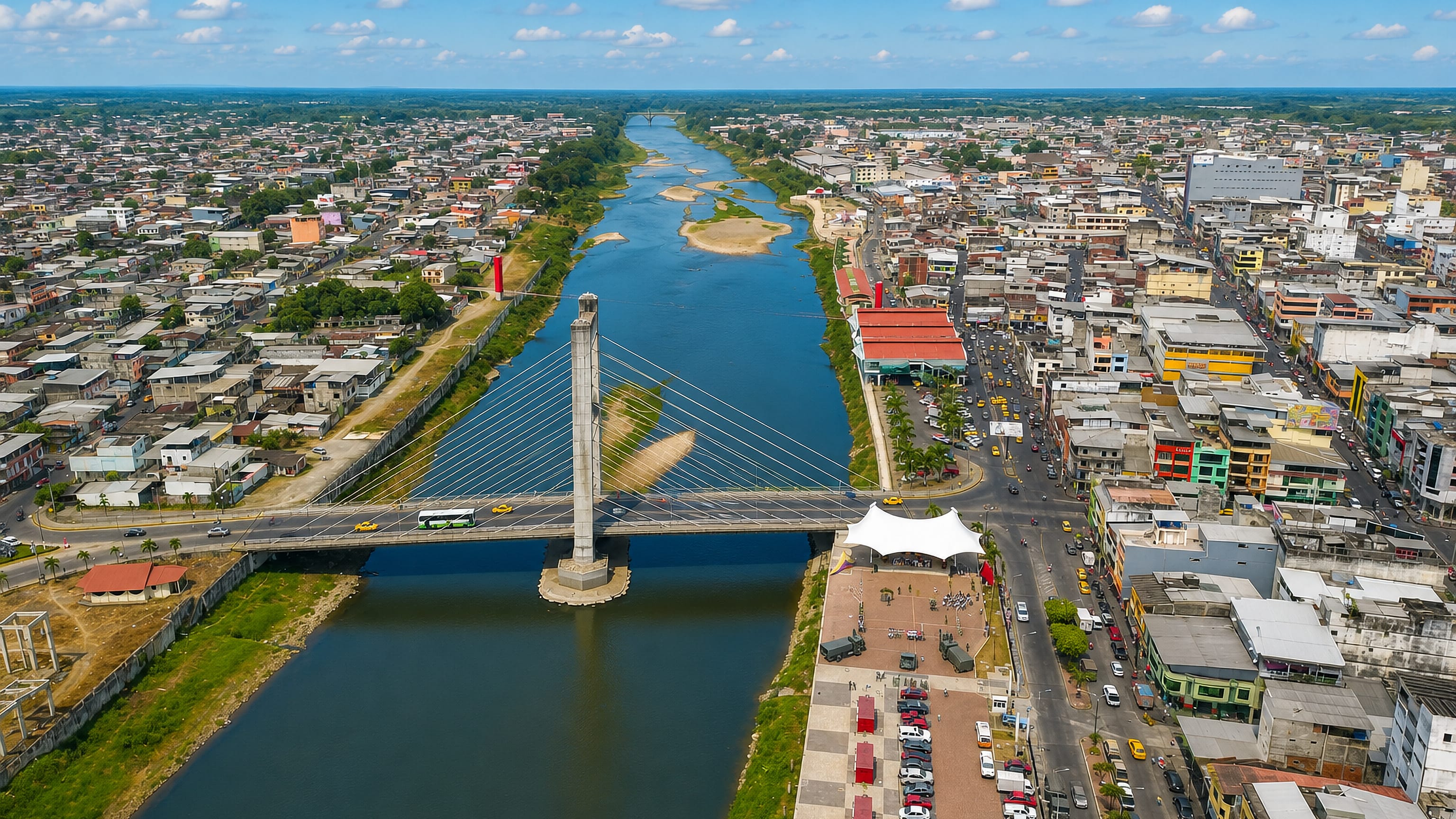 Aerial view of Quevedo, Ecuador, split by its river with a cable-stayed bridge and riverside promenade