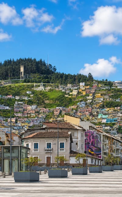 Colourful hillside homes of La Libertad rise above a paved boulevard in central Quito, Ecuador.