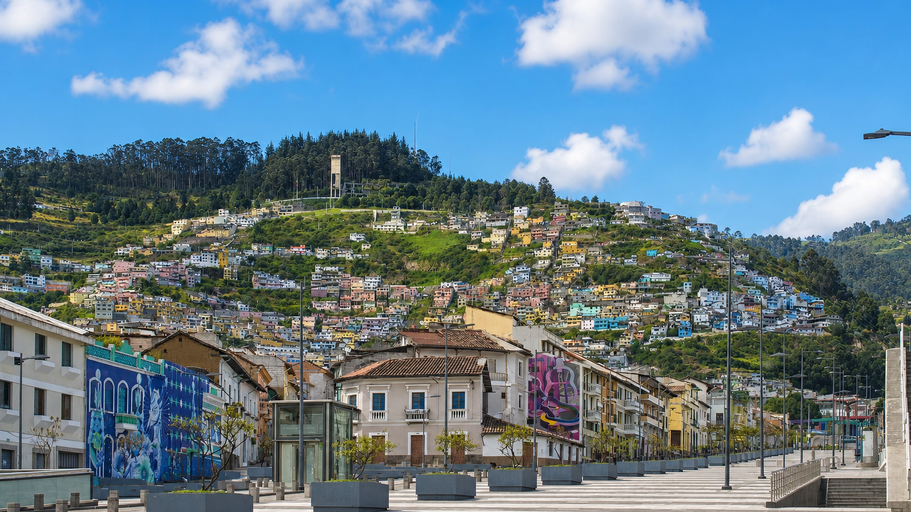 Colourful hillside homes of La Libertad rise above a paved boulevard in central Quito, Ecuador.