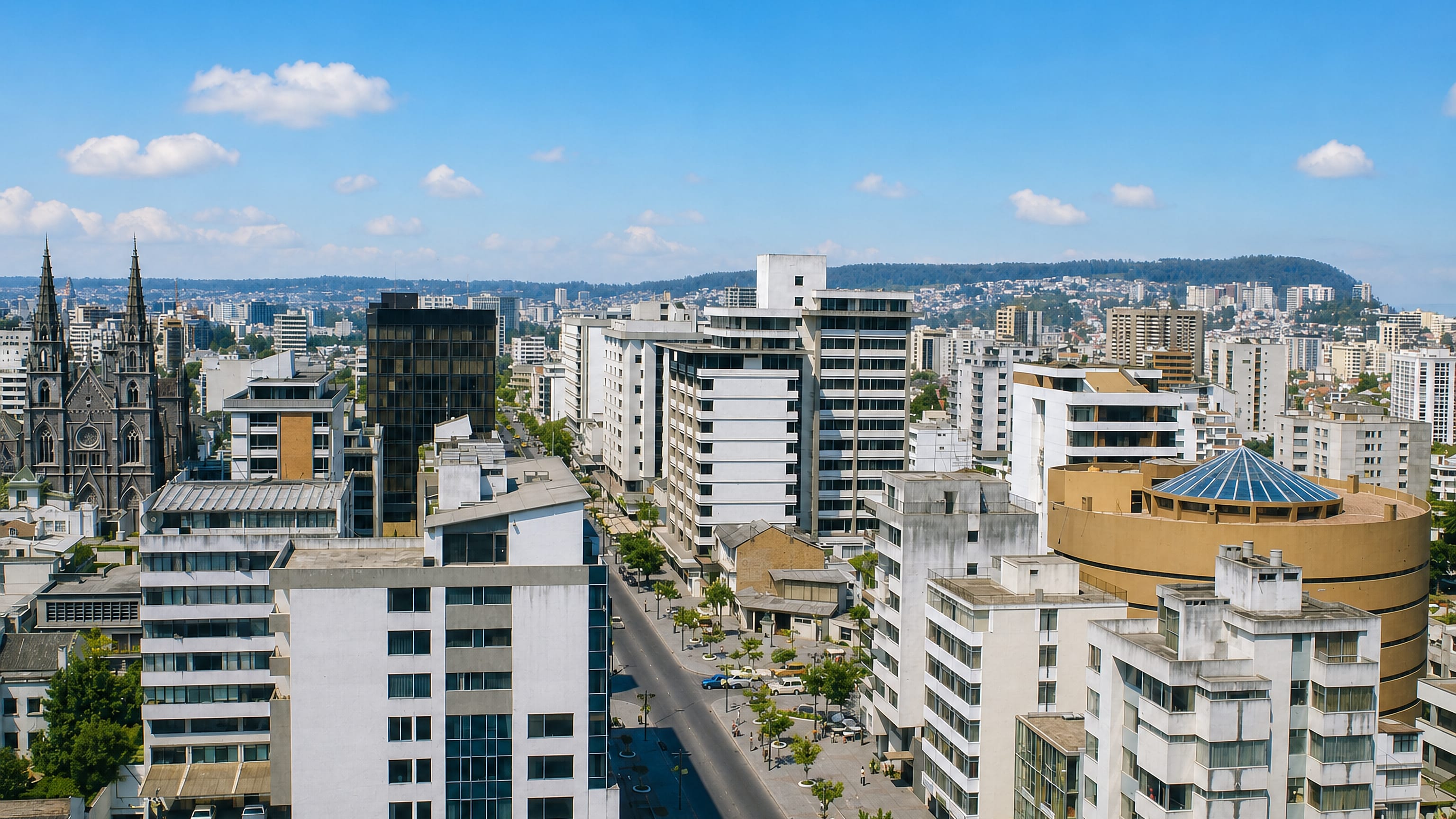 High view over La Mariscal in Quito, with mid-rise towers, a domed cultural building and Andean hills behind