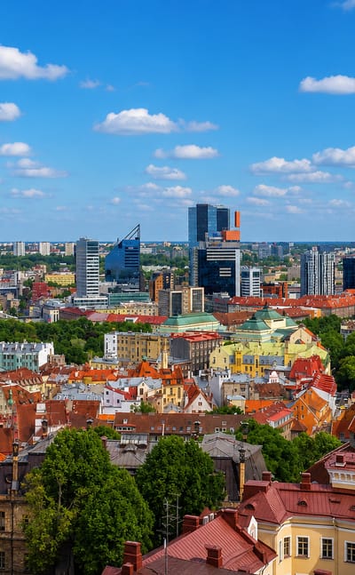 Tallinn Old Town rooftops with St. Olaf's church tower and the modern business-district skyline beyond