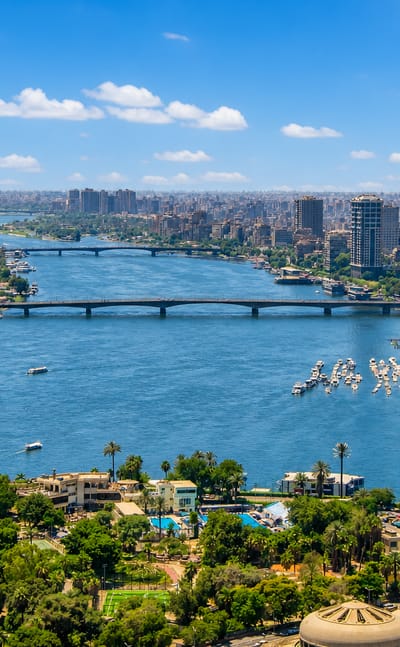 Cairo Nile view over Buluq Abu al-Ila with the cylindrical Gezira Nile tower, river bridges and moored boats