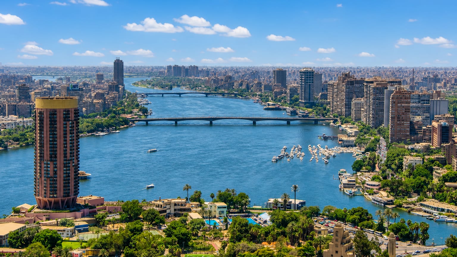 Cairo Nile view over Buluq Abu al-Ila with the cylindrical Gezira Nile tower, river bridges and moored boats