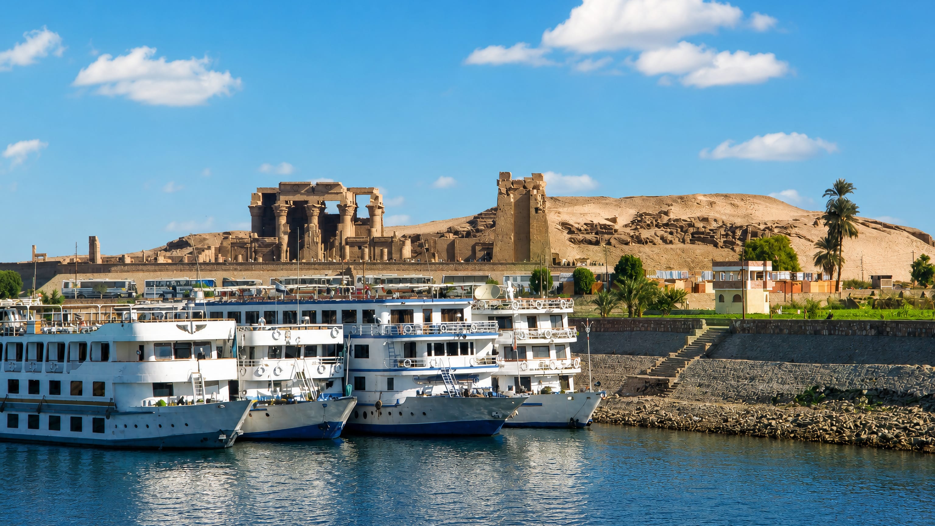 Nile cruise boats moored below the ancient Temple of Kom Ombo on its desert ridge in Kom Ombo, Egypt