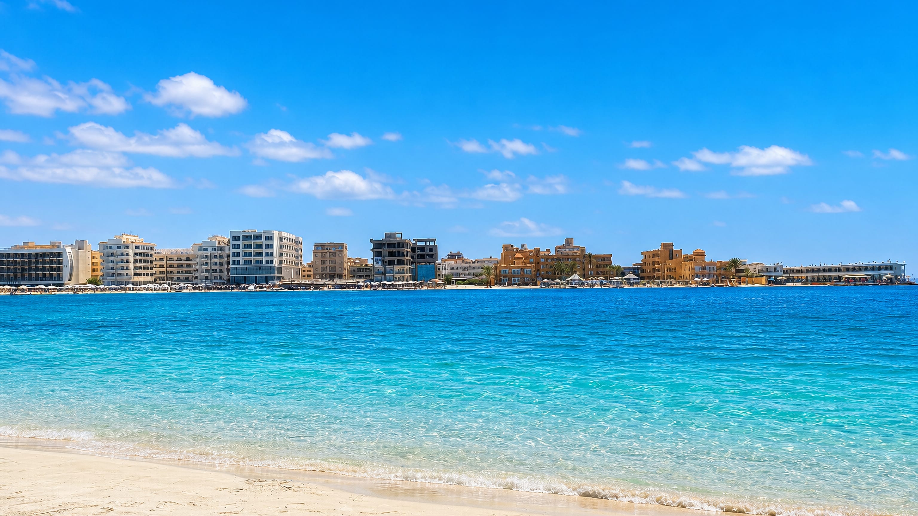 Turquoise bay and white-sand beach fronting the low-rise corniche hotels of Marsa Matruh, Egypt.