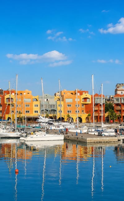 Colourful waterfront buildings and moored yachts at Hurghada Marina with calm reflections
