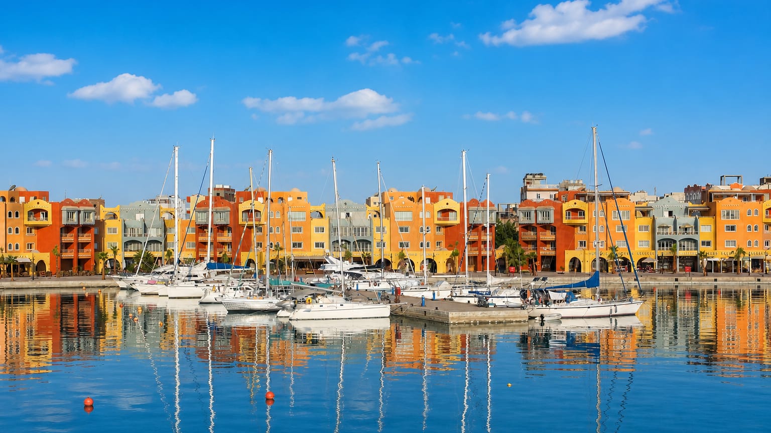 Colourful waterfront buildings and moored yachts at Hurghada Marina with calm reflections